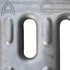 Close-up of a gray metal plate with the letters A and C and elongated oval slots.