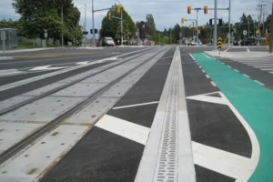 Wide street with tram rails running down the center, a green bike lane on the right, and multiple crosswalks and traffic signals ahead.
